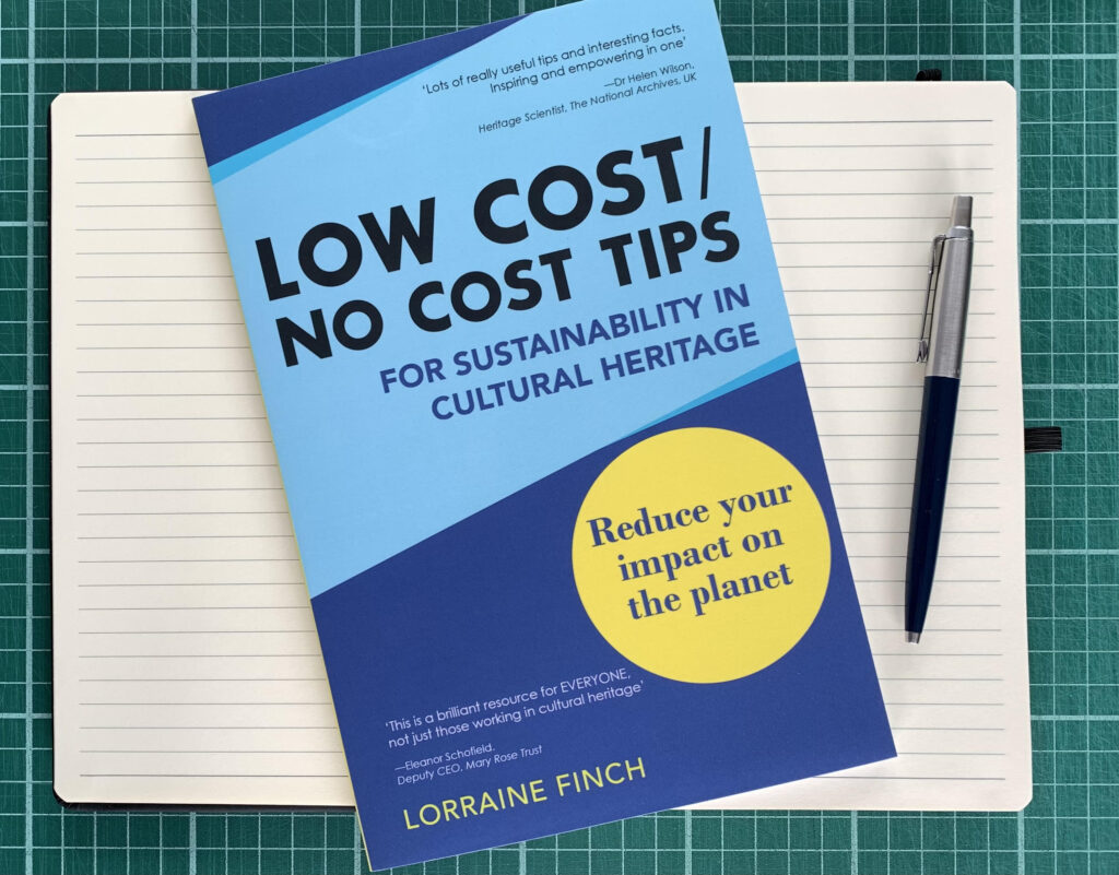 A copy of Low Cost/No Cost Tips for Sustainability in Cultural Heritage on top of an open notebook with a pen.